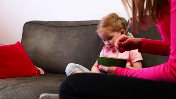 Mãe alimenta uma menina que não pode tirar os olhos de seu smartphone — Vídeo de Stock