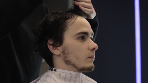 Couper les cheveux mouillés d'un jeune homme dans un barbeshop — Video
