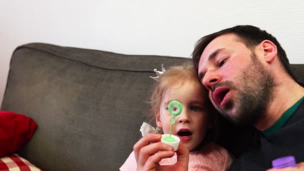 A father and his little child girl blows a soap bubble together in slow motion. — Stock Video