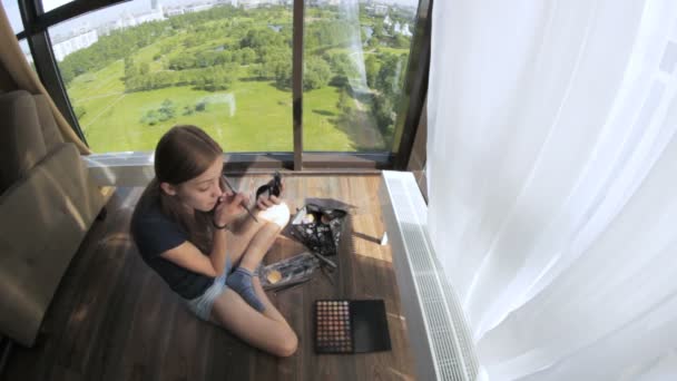 Menina bonita fazendo maquiagem na janela — Vídeo de Stock