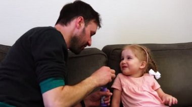 Bir baba kızı için sabun köpüğü darbeler. Bir bebek güler.
