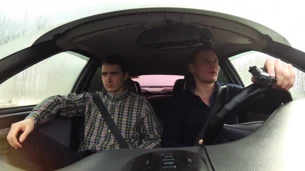 Two serious mens drive in a car. The driver with a gun in his hands. — Stock Video