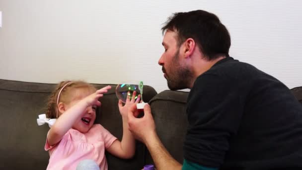 Ein Vater bläst große Seifenblase für seine süße Tochter. — Stockvideo