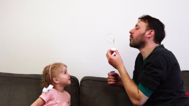 Un giovane padre felice soffia una bolla di sapone e si apre sul naso dei suoi bambini . — Video Stock