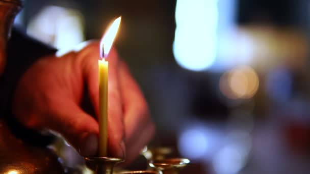 En person sätter ett enda ljus på altaret i en ortodox kyrka — Stockvideo