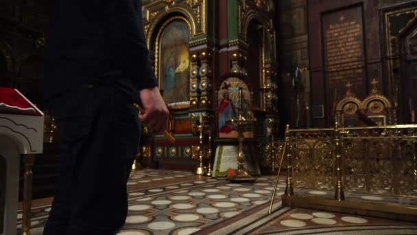 Un homme tient dans les mains des bougies de l'Eglise. Il y a beaucoup d'icônes orthodoxes en arrière-plan . — Video