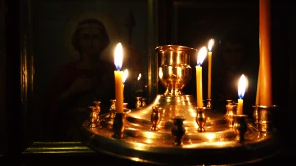 Video close-up in de in een donkere kerk met het branden van kaarsen. Camera pan. — Stockvideo
