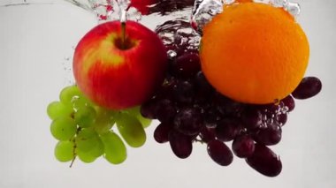 Elma, portakal ve üzüm su kabarcıkları yavaş hareket ile içine düşme. Beyaz arka plan üzerinde meyve.