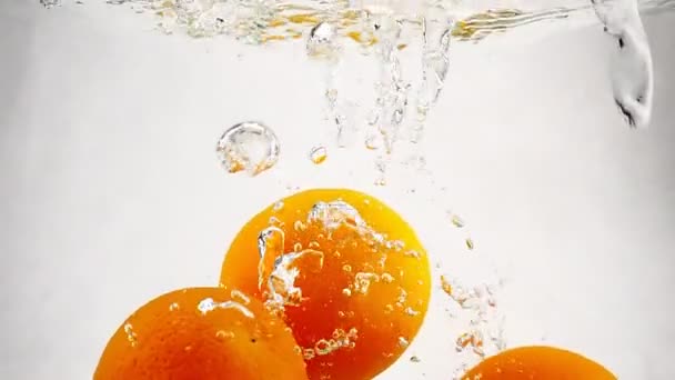 Sinaasappelen ondergedompeld in het water met de bubbels. Fruit citrus in slowmotion op geïsoleerde witte achtergrond. — Stockvideo