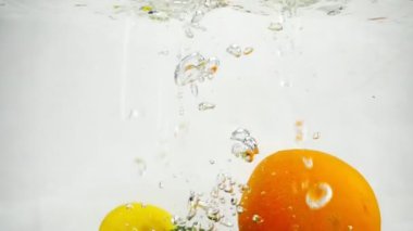 Limon, limon ve portakal su kabarcıkları ile içine düşme slow motion video.