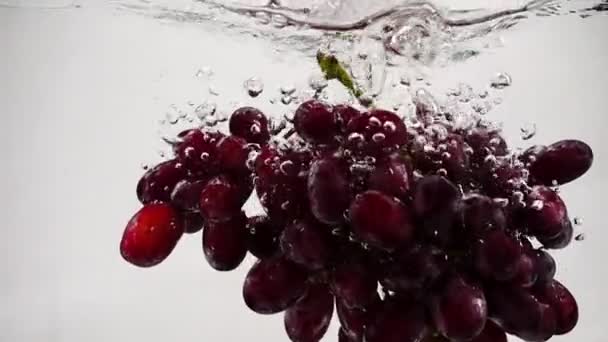 Vídeo em câmara lenta de uvas vermelhas. Bando de uvas estão imersas em água com bolhas . — Vídeo de Stock