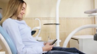 İzlerken ve kameraya gülümseyen diş hekimleri sandalyede oturan kız