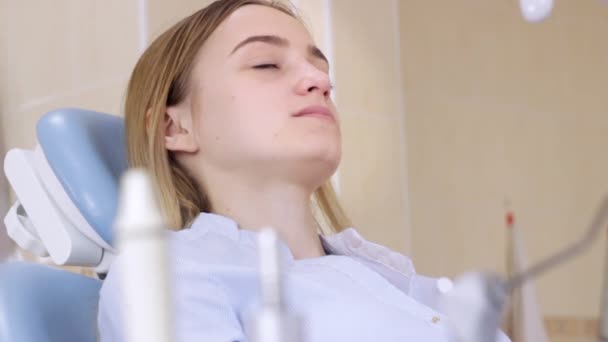 El consultorio de dentistas, chica en silla de dentistas sonríe y habla con el médico — Vídeo de stock
