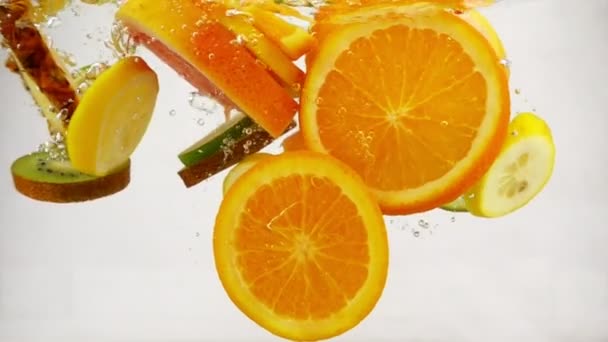 Multifruit řezy různých druhů ovoce, spadnout do vody s tryskající a bubliny, zpomalené detail — Stock video