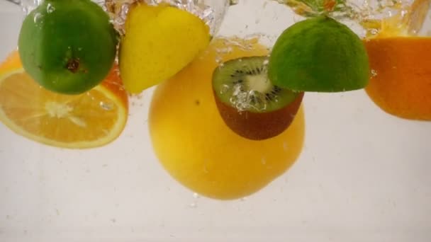 Conjunto de frutas múltiplas, metades de frutas diferentes caindo com salpicos na água, câmera lenta close-up — Vídeo de Stock