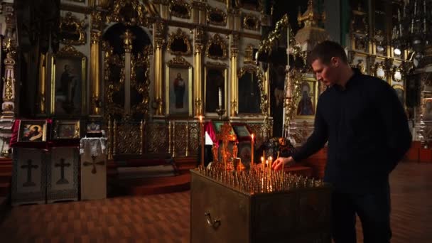 Elets, Ruská federace - 2 dubna 2018: Ortodoxní člověk zapálí svíčku v chrámu. Existuje mnoho ikon Christian Church v pozadí. — Stock video