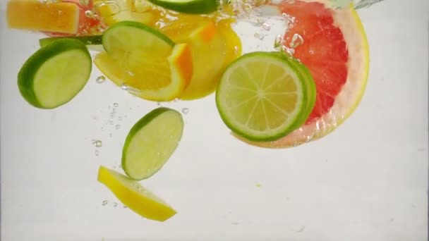 Zitrusfrüchte Limette, Zitrone, Orange, Grapefruit fallen mit Spritzern und Blasen ins Wasser, Zeitlupe Nahaufnahme