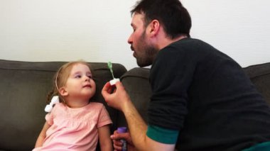 Bir baba onun kızı yüz yavaş hareket içine bir sabun köpüğü darbeler.