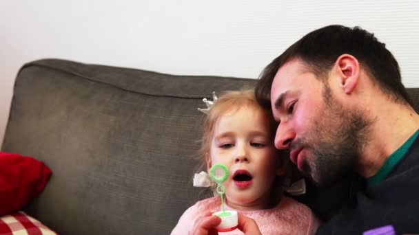 Ein Vater und sein Kind pusten zusammen eine schillernde Seifenblase. — Stockvideo