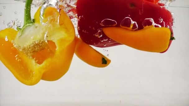 Pimenta chili e páprica girando na água com salpicos e bolhas, câmera lenta close-up — Vídeo de Stock