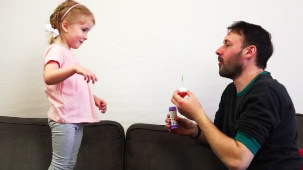 Een vader blaast een zeepbel en zijn dochter knalt het in slowmotion. — Stockvideo
