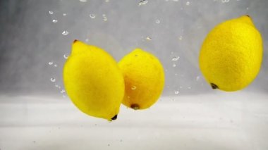 Limon düşen ve su kabarcıkları ile dönen. Meyve ağır çekimde video.