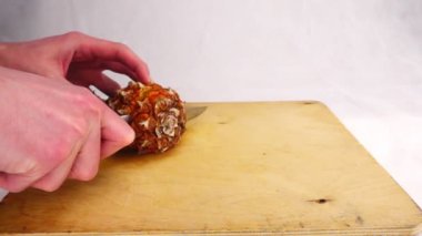 Ananas bir ahşap tahta üzerinde bir bıçak ile kesme