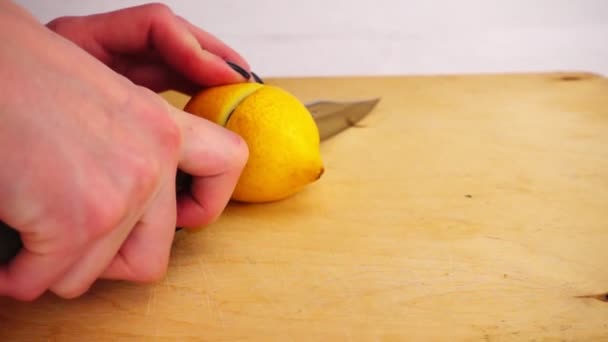 Zitrone mit einem Messer auf einem Holzbrett schneiden — Stockvideo