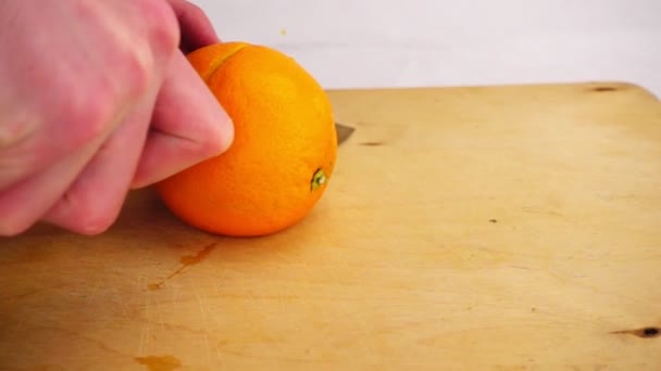 Taglio arancio con un coltello su una tavola di legno — Video Stock