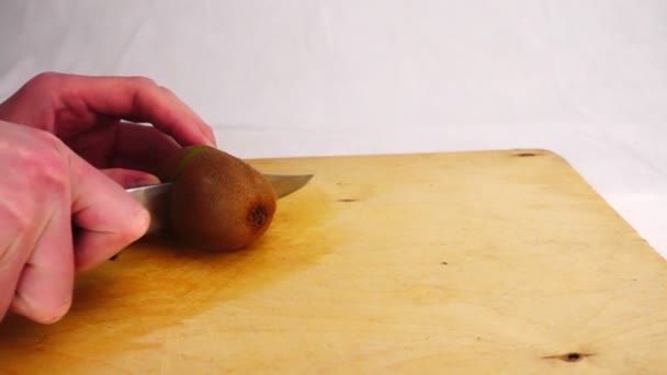 एक लकड़ी के बोर्ड पर चाकू के साथ कीवी काटना — स्टॉक वीडियो