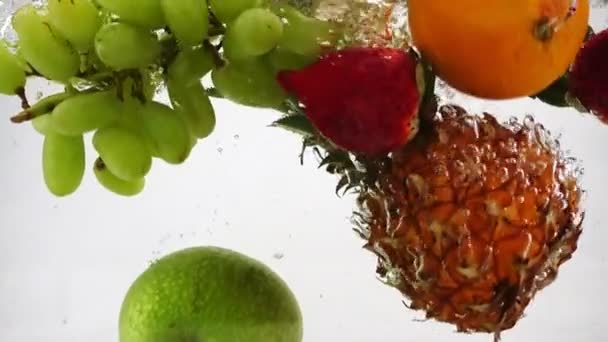 Apple, kiwi, pomarańcza, gruszka, cytryny, winogrona, ananas i berry wpada do wody. Wideo na na białym tle. — Wideo stockowe