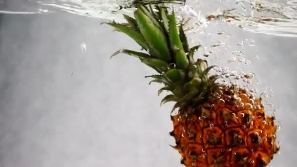 La piña cae al agua con un montón de pequeñas burbujas. Video de piña sobre fondo blanco aislado . — Vídeos de Stock