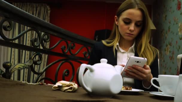 Деловая леди в ресторане листает через социальную сеть на смартфоне — стоковое видео