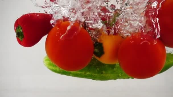 Массив свежих овощей, огурец, перец и помидоры падает в воду, замедленное движение крупным планом — стоковое видео
