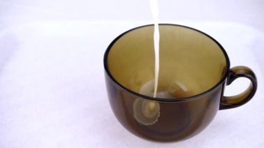 Süt şeffaf cam bardağa dökülür. Süt yavaş çekimde bir jet.