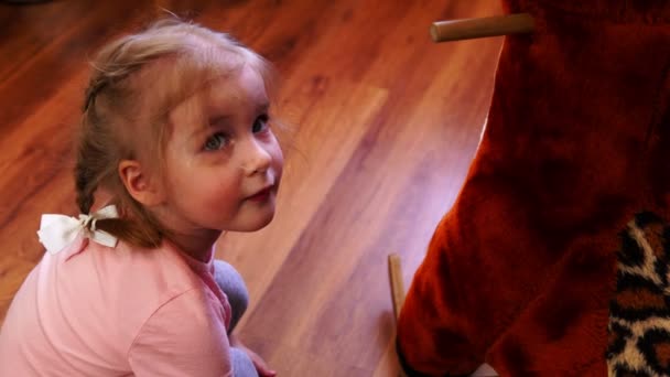 Маленькая девочка чинит игрушечного оленя. Ребенок поворачивает винт отверткой . — стоковое видео