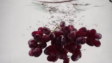 Ağır çekimde video kırmızı üzüm. Olgun üzüm demet su kabarcıkları ile batırılır.