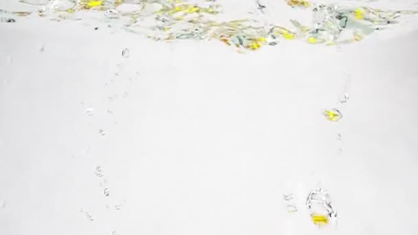 Laranja suculenta e limão caem na água com bolhas. Frutas em câmera lenta sobre fundo branco isolado . — Vídeo de Stock