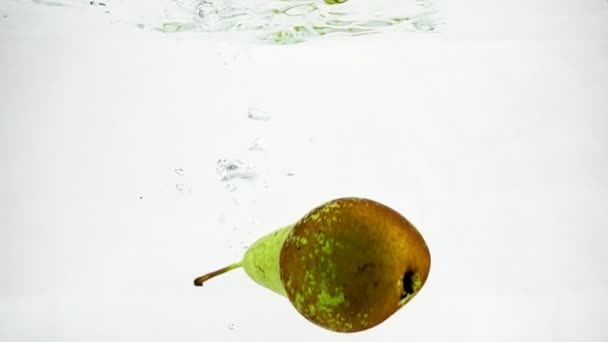 Pera verde succosa su fondo bianco isolato al rallentatore. Conferenza pera è immersa in acqua con bolle . — Video Stock