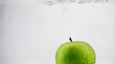 Elma su tankının içinde yavaş bir hızda atlıyor. Elma izole beyaz zemin üzerine.