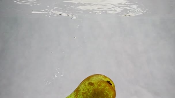 Birne wirbelt im Wasser mit Blasen in Zeitlupe. — Stockvideo