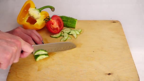 Corte de pepino em fatias com uma faca em uma placa de madeira, câmera lenta — Vídeo de Stock