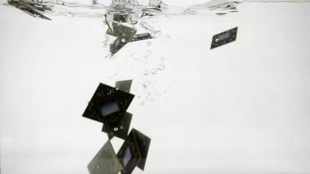 Микрочипы падают в воду, замедляя движение на белом фоне — стоковое видео