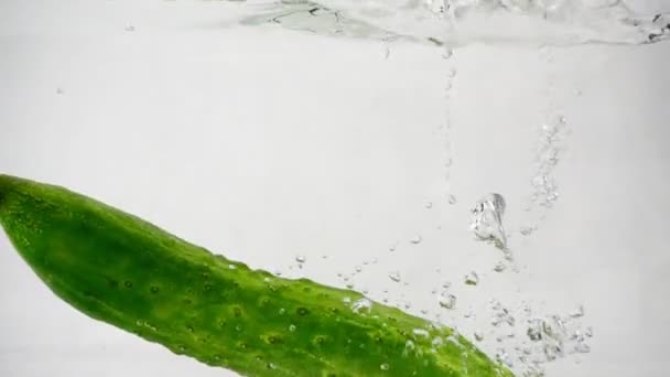 Зеленый огурец падает в воду с брызгами и пузырьками — стоковое видео