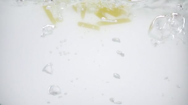 Levné těstoviny bez chuti hozené do bahnité vroucí vody, zpomalený pohyb na bílém pozadí, — Stock video