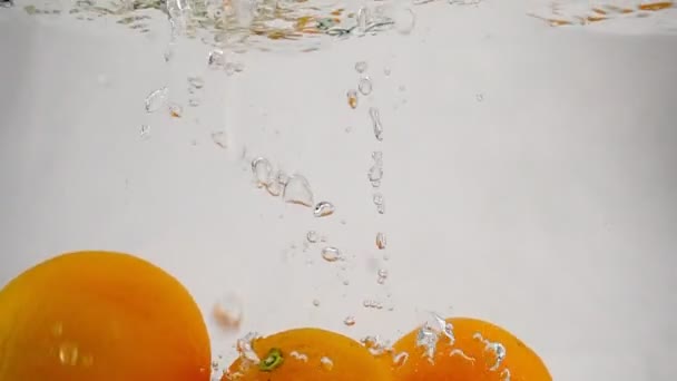 De sinaasappel die in water valt met belletjes. Video in slow motion. Fruit op geïsoleerde een witte achtergrond. — Stockvideo