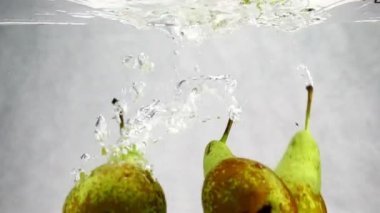 Yeşil armut düşüyor suya bir sürü küçük kabarcıklar ile. Meyve izole beyaz zemin üzerine video.