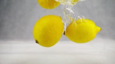 Sarı limon su kabarcıkları ile düşüyor. Ağır çekim bir video. Beyaz bir arka plan üzerinde izole meyve.