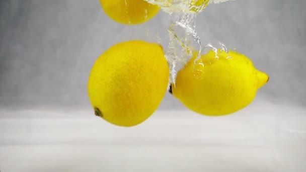 Limoni gialli che cadono in acqua con bolle. Video al rallentatore. Frutta isolata su fondo bianco . — Video Stock
