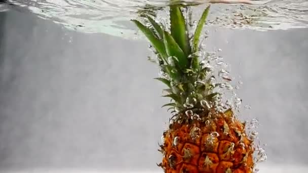 Abacaxi cai na água com bolhas. Vídeo em câmera lenta . — Vídeo de Stock